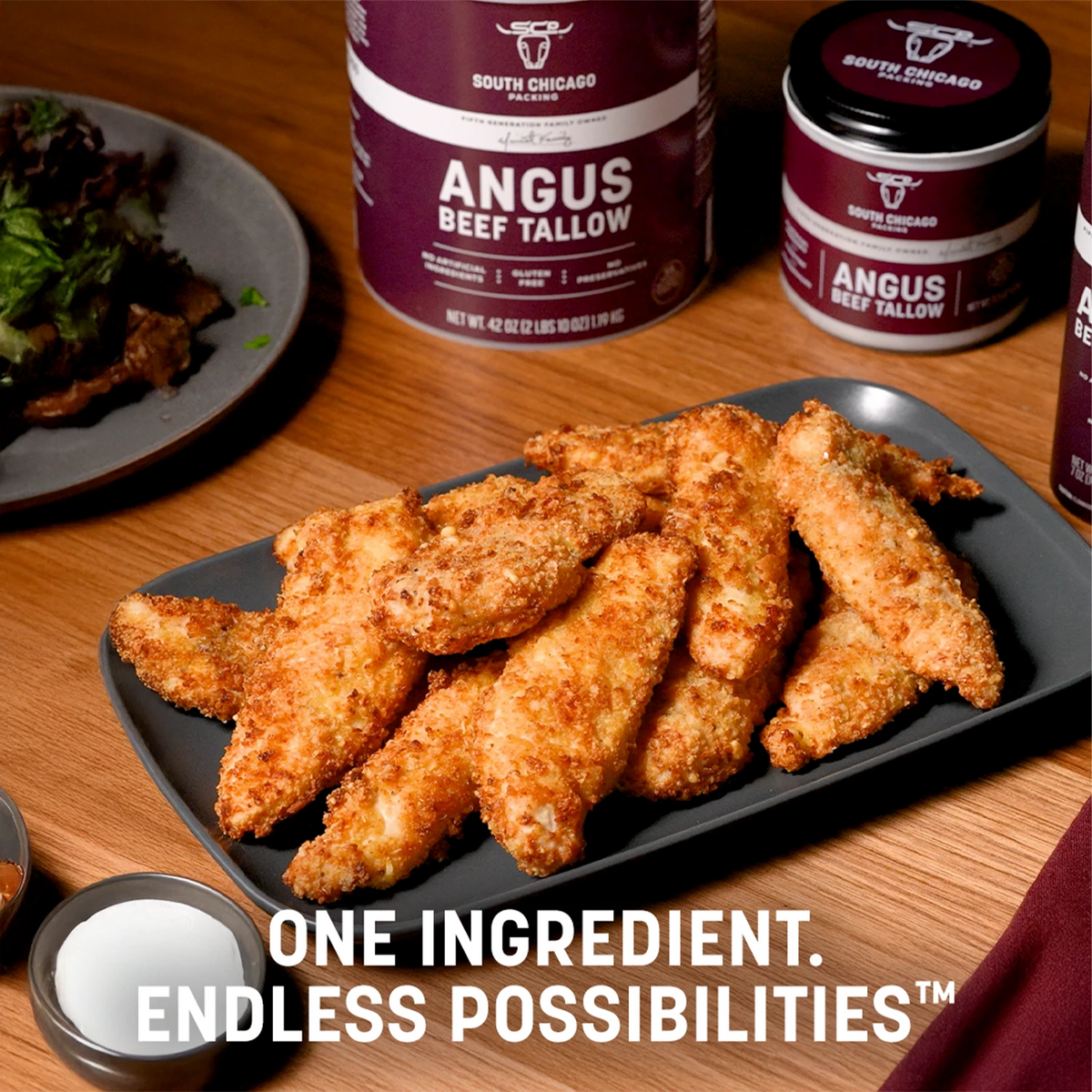 Breaded chicken tenders on a dark plate in a restaurant setting, with South Chicago Creamery Angus Beef Tallow tubs in the background and promotional text at the bottom.