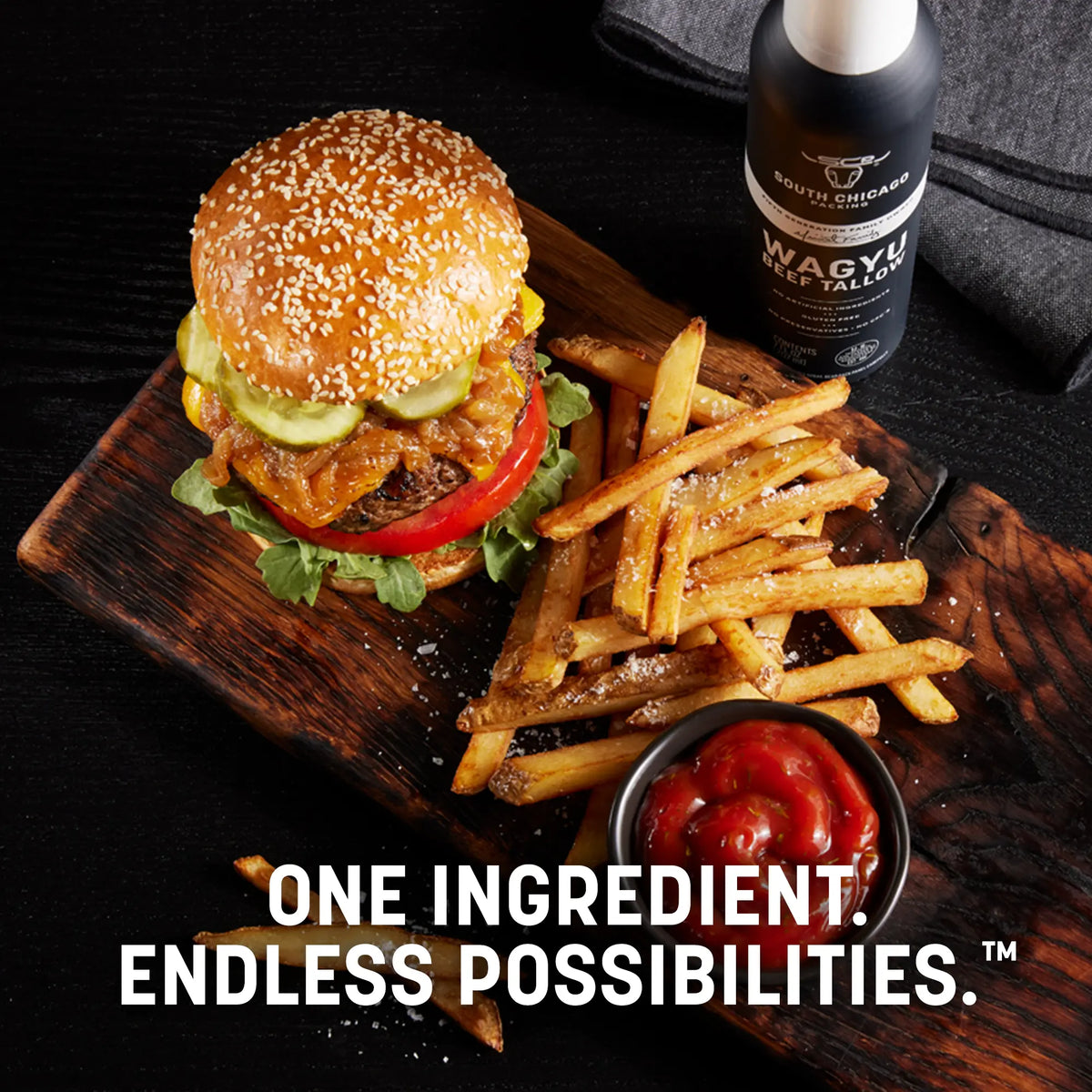 Burger and fries on a wooden board with a bottle of South African Wagyu beef tallarin in the background.