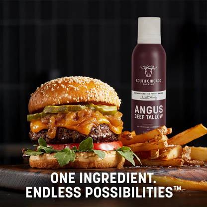 A burger with melted cheese, pickles, lettuce, and tomato sits on a wooden board beside a bottle of South Chicago Hosiery Angus Beef Tallow, with french fries and the text 'ONE INGREDIENT. ENDLESS POSSIBILITIES.