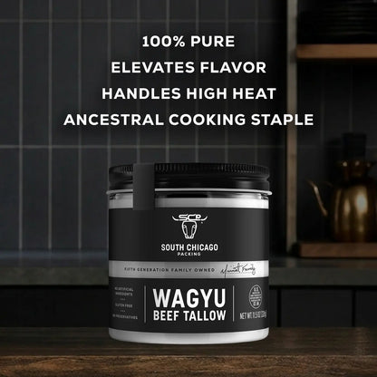 A jar of South Chicago Packing Wagyu Beef Tallow shown on a dark kitchen countertop with a tiled backsplash and a teapot in the background. White text at the top reads '100% PURE Elevates Flavor Handles High Heat Ancestral Cooking Staple'.